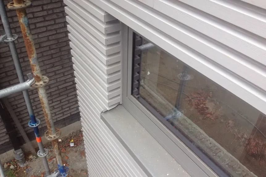 Detailopname van de verticale metalen gevelbekleding en raamomlijsting, uitgevoerd door Dakwerken De Haes in Waarloos, Kerkelei.