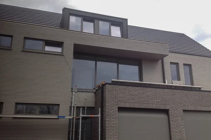 Afgewerkte moderne woning in Waarloos, Kerkelei met donker leien dak, dakkapel en gevelbekleding door Dakwerken De Haes.