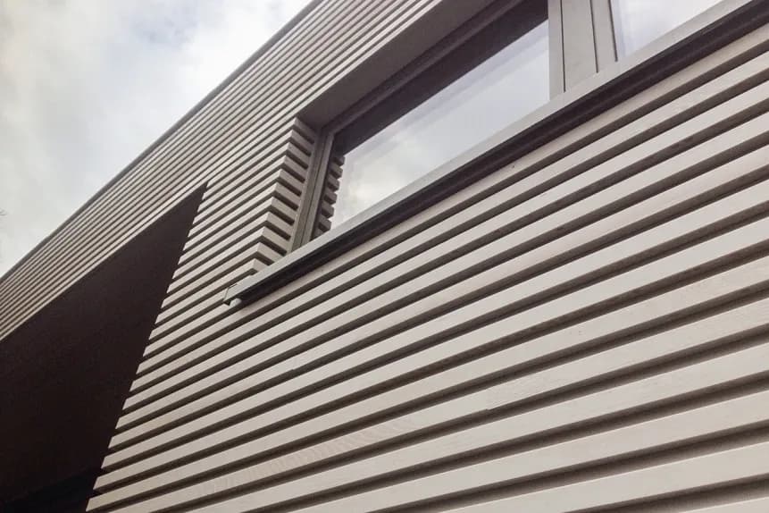 Detailopname van de horizontale gevelbekleding en dakrand, vakkundig afgewerkt door Dakwerken De Haes in Waarloos, Kerkelei.