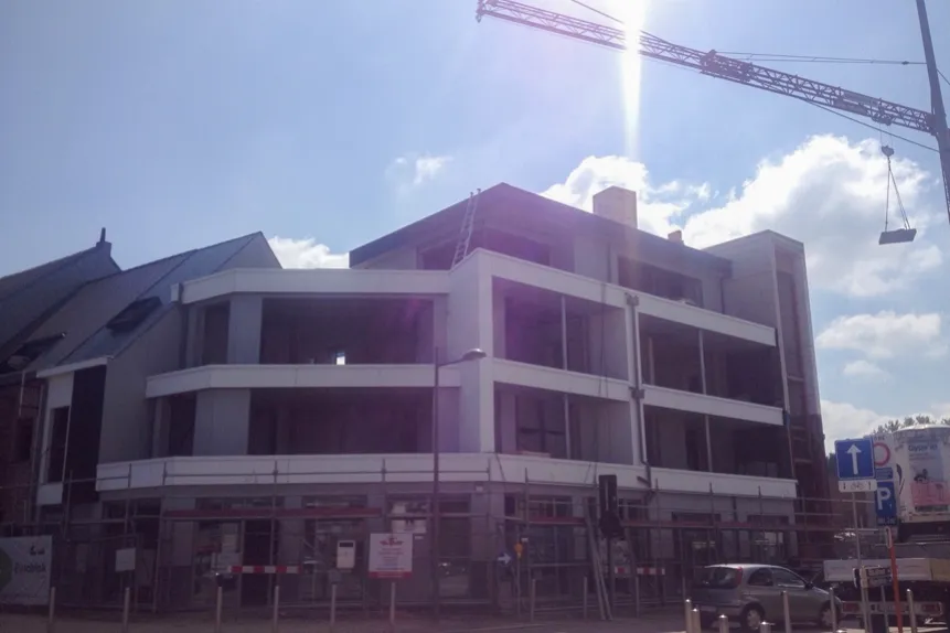 Afgewerkte gevelbekleding in wit en donker op een modern commercieel gebouw in Sint-Katelijne-Waver, Dorp, uitgevoerd door Dakwerken De Haes.